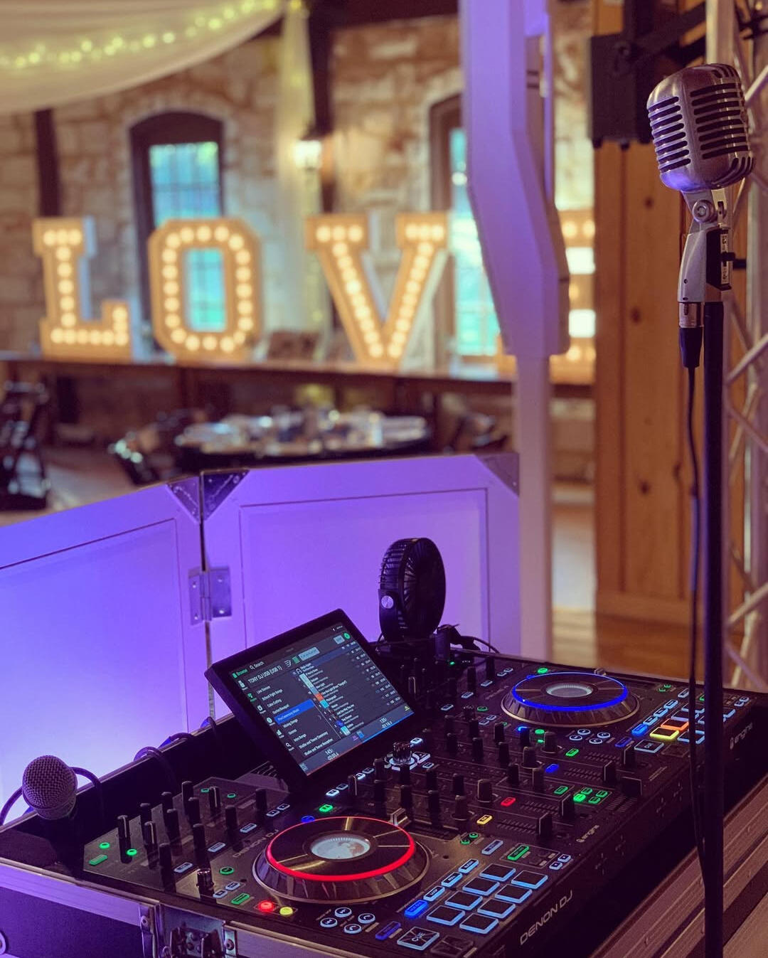 DJ Wedding Setup DJ equipment and a microphone positioned in front of a large illuminated love sign, creating a vibrant atmosphere.